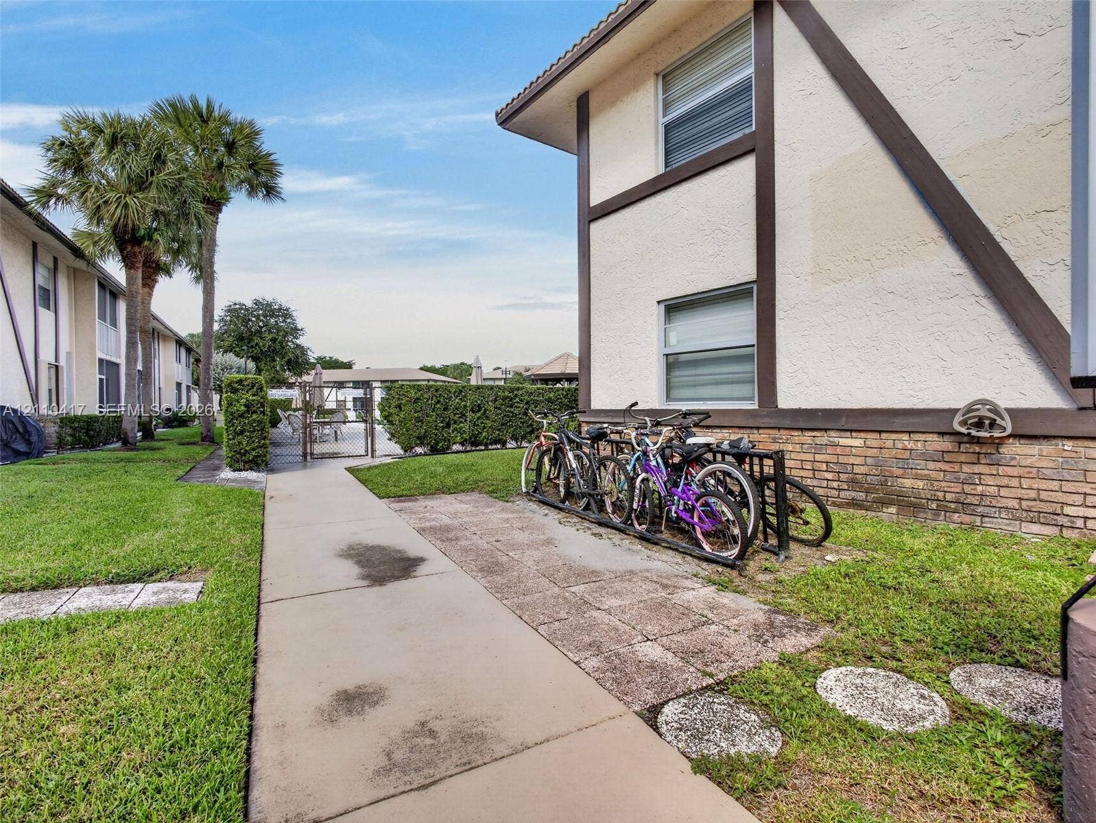 2369 NW 89th Drive, #514, Coral Springs, FL 33065 Exterior facade featuring stucco siding with timber accents, brick masonry base, concrete walkways, and manicured landscaping