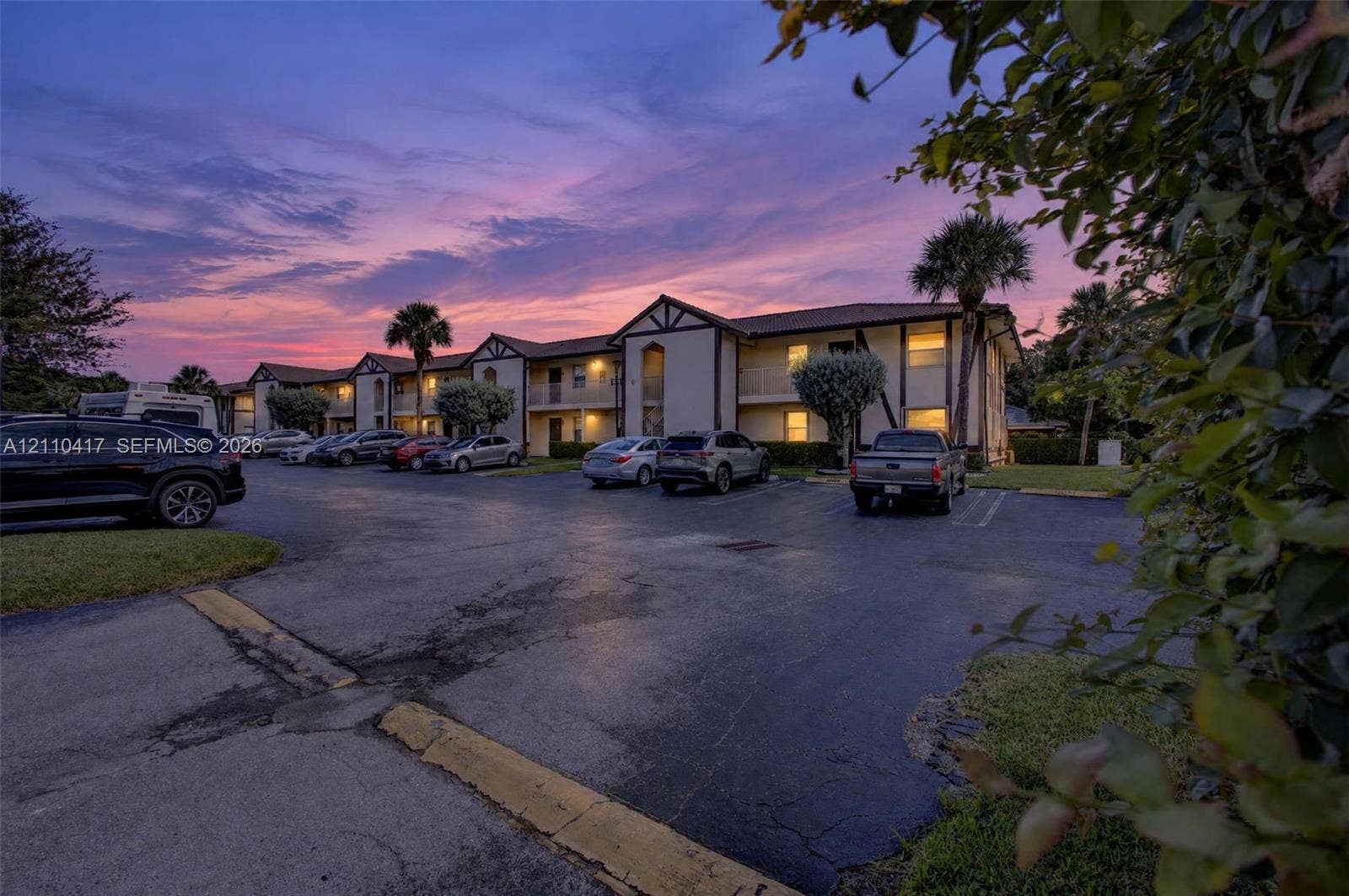 2369 NW 89th Drive, #514, Coral Springs, FL 33065 Multi-level building exterior featuring a stucco facade with dark trim accents, a tile roof, covered entryways, and designated asphalt parking
