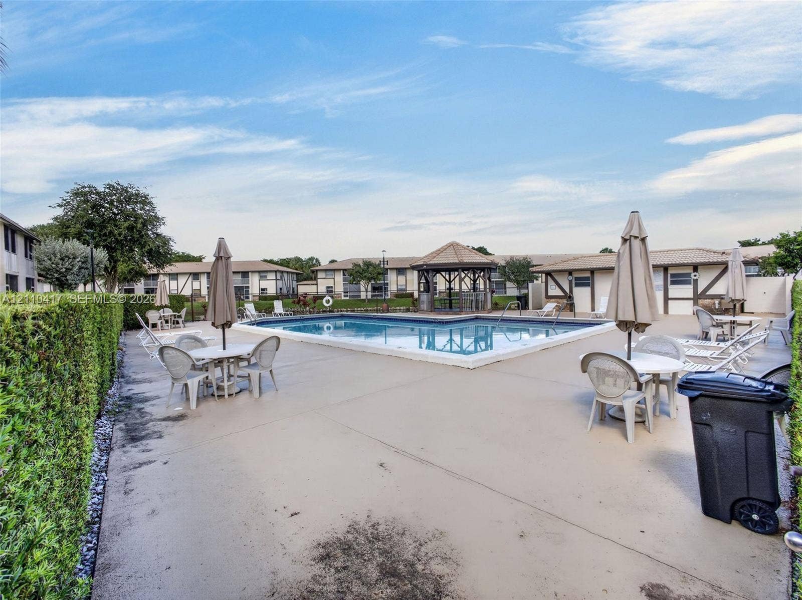 2369 NW 89th Drive, #514, Coral Springs, FL 33065 In-ground swimming pool featuring a concrete deck, built-in gazebo, and manicured hedge perimeter