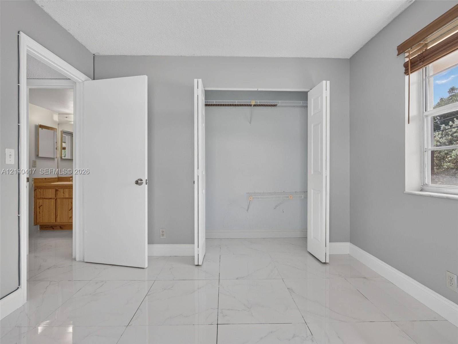 2369 NW 89th Drive, #514, Coral Springs, FL 33065 Neutral-toned interior featuring large-format tile flooring, a dual-door closet with built-in wire shelving, and a window with wood-finish blinds