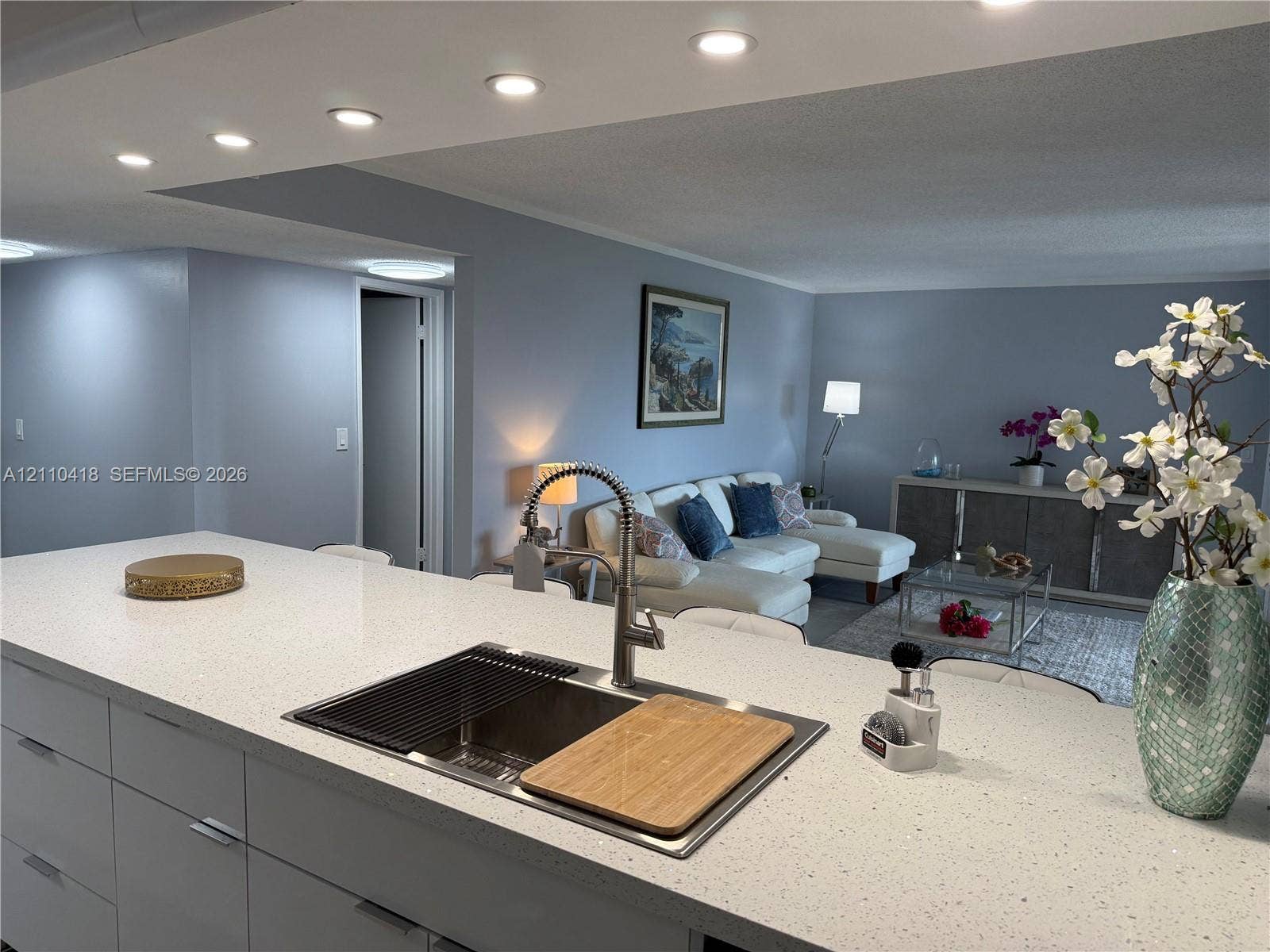 950 Egret Circle, #5409, Delray Beach, Delray Beach, FL 33444 Kitchen island featuring a stone-composite countertop, undermount stainless steel sink, gooseneck faucet, and flat-panel cabinetry with recessed lighting