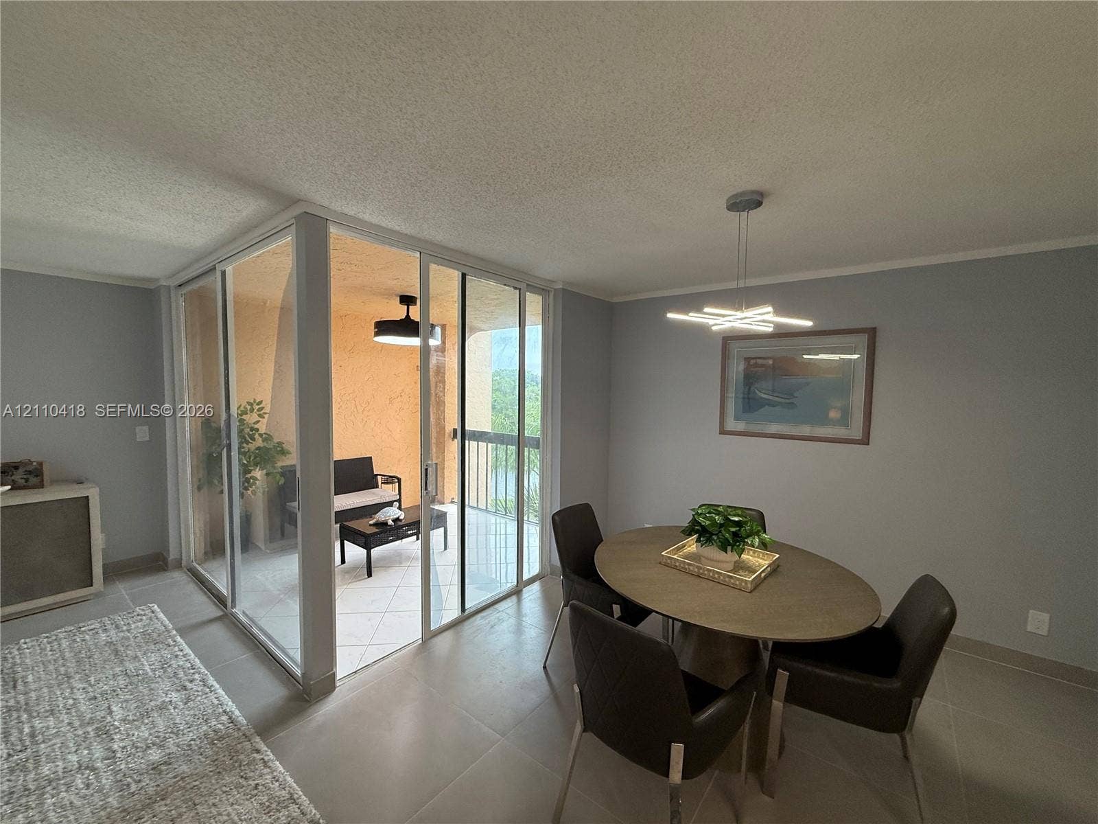 950 Egret Circle, #5409, Delray Beach, Delray Beach, FL 33444 Enclosed balcony featuring floor-to-ceiling glass paneling and tile flooring, paired with large-format neutral floor tiling throughout and a contemporary geometric pendant light fixture