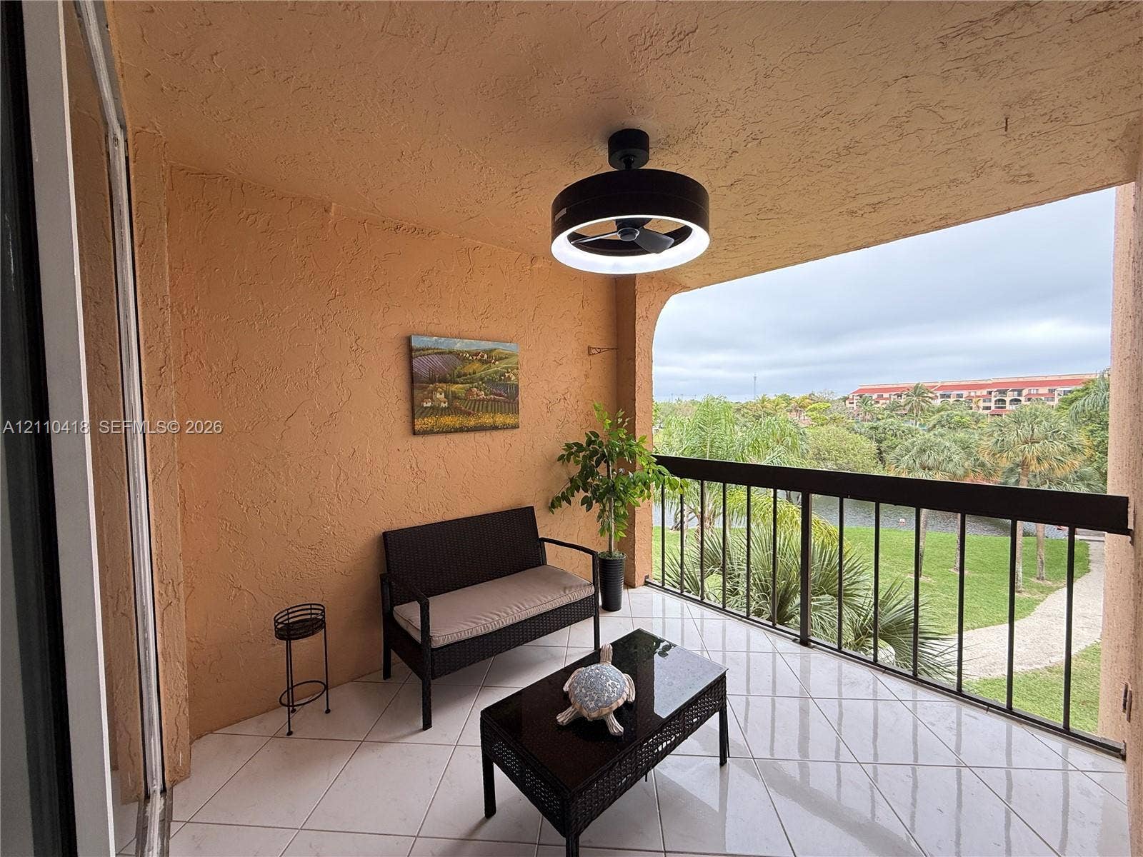 950 Egret Circle, #5409, Delray Beach, Delray Beach, FL 33444 Covered balcony featuring tile flooring, textured wall finishes, and a contemporary circular LED ceiling fan with integrated lighting