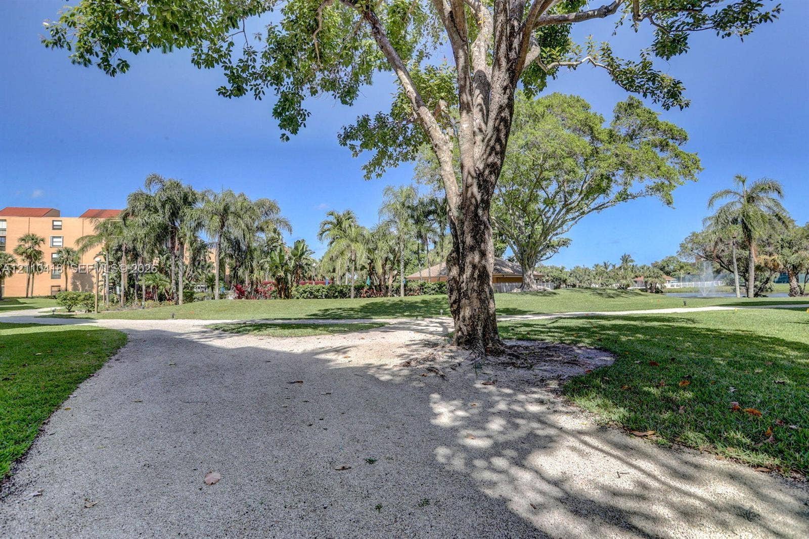 950 Egret Circle, #5409, Delray Beach, Delray Beach, FL 33444 Expansive grounds featuring a meandering gravel pathway, mature trees, manicured lawns, and palm landscaping