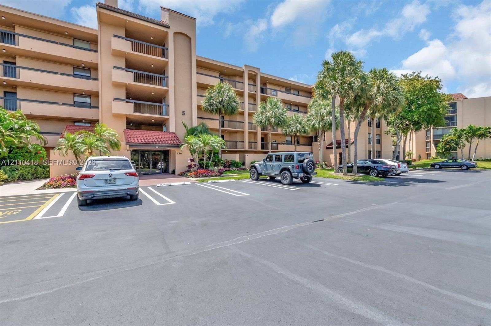 950 Egret Circle, #5409, Delray Beach, Delray Beach, FL 33444 Multi-story residential building featuring covered balconies, terracotta-style roof accents, and mature palm tree landscaping