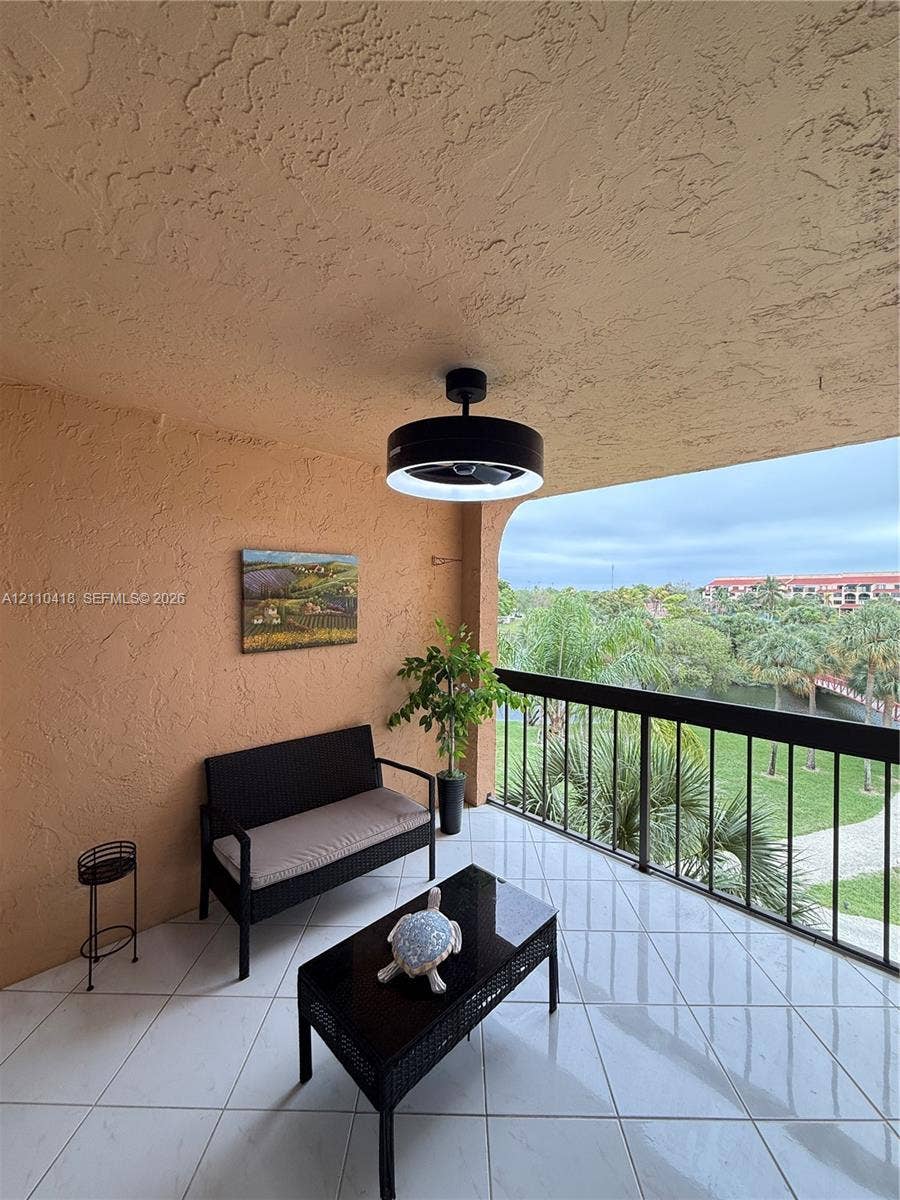 950 Egret Circle, #5409, Delray Beach, Delray Beach, FL 33444 Covered balcony featuring white tile flooring, textured wall finishes, and a matte black ceiling fan with an integrated circular light fixture