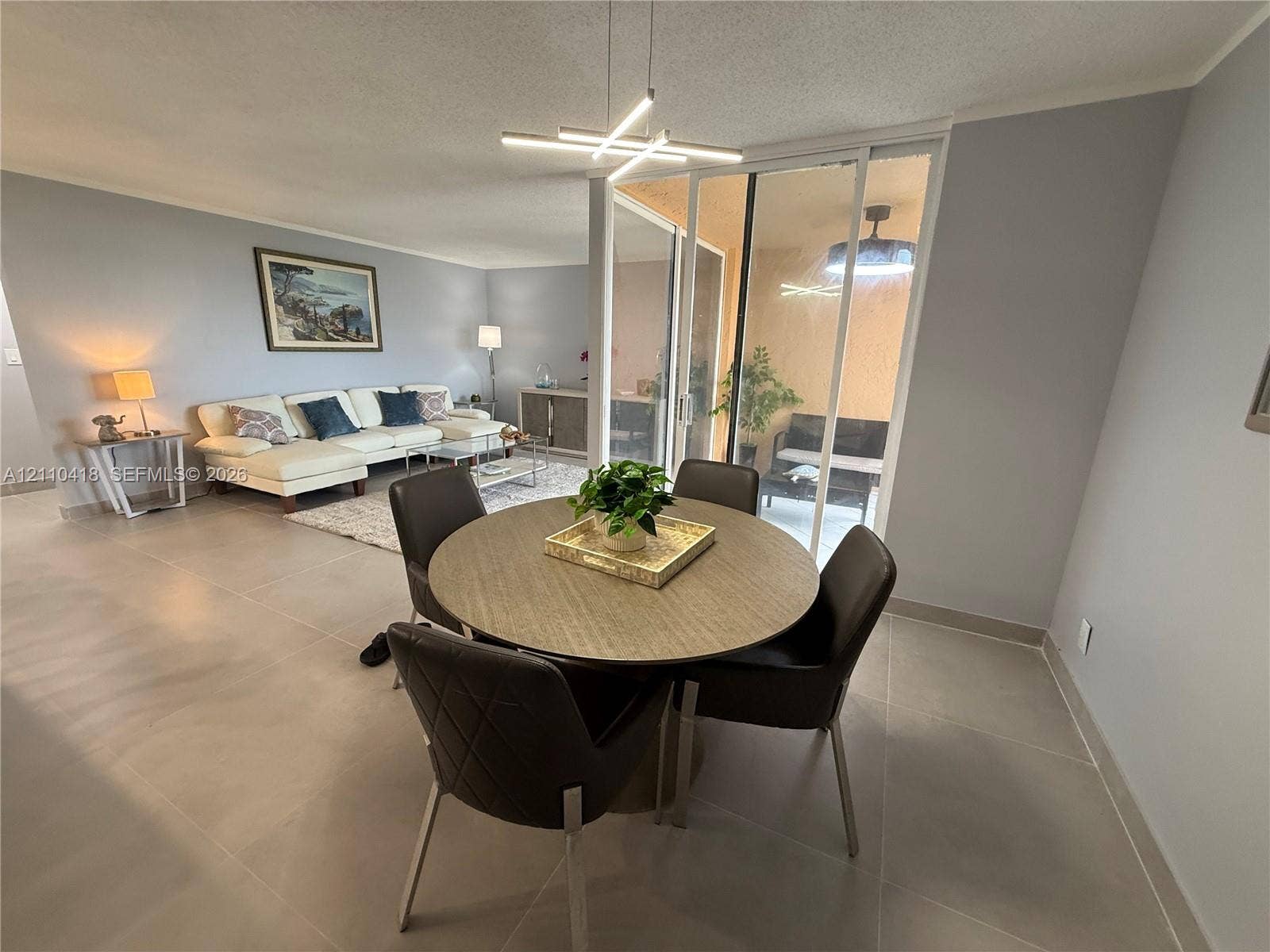 950 Egret Circle, #5409, Delray Beach, Delray Beach, FL 33444 Large-format tile flooring, modern geometric chandelier, and sliding glass door access to an enclosed patio