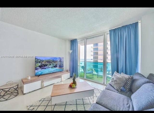 Floor-to-ceiling glass sliding doors opening to a balcony with metal and glass railing, smooth finished ceilings, and neutral tile flooring