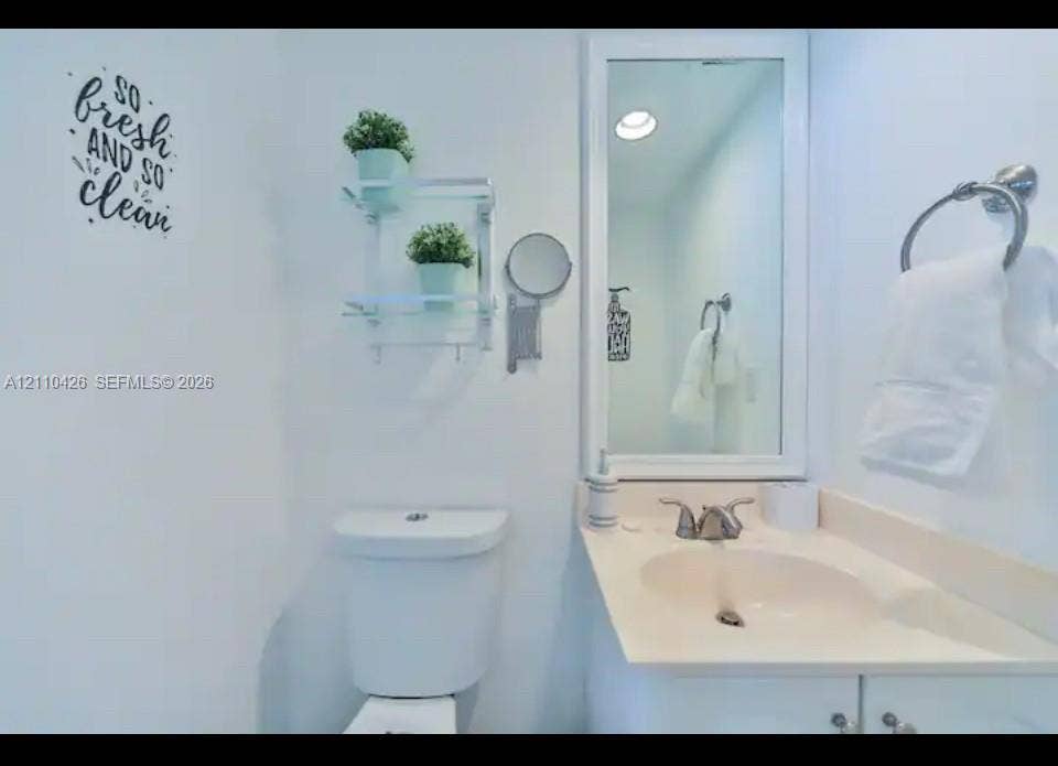 Bathroom featuring a vanity with an integrated sink and countertop, framed wall mirror, polished chrome dual-handle faucet, and polished chrome towel ring