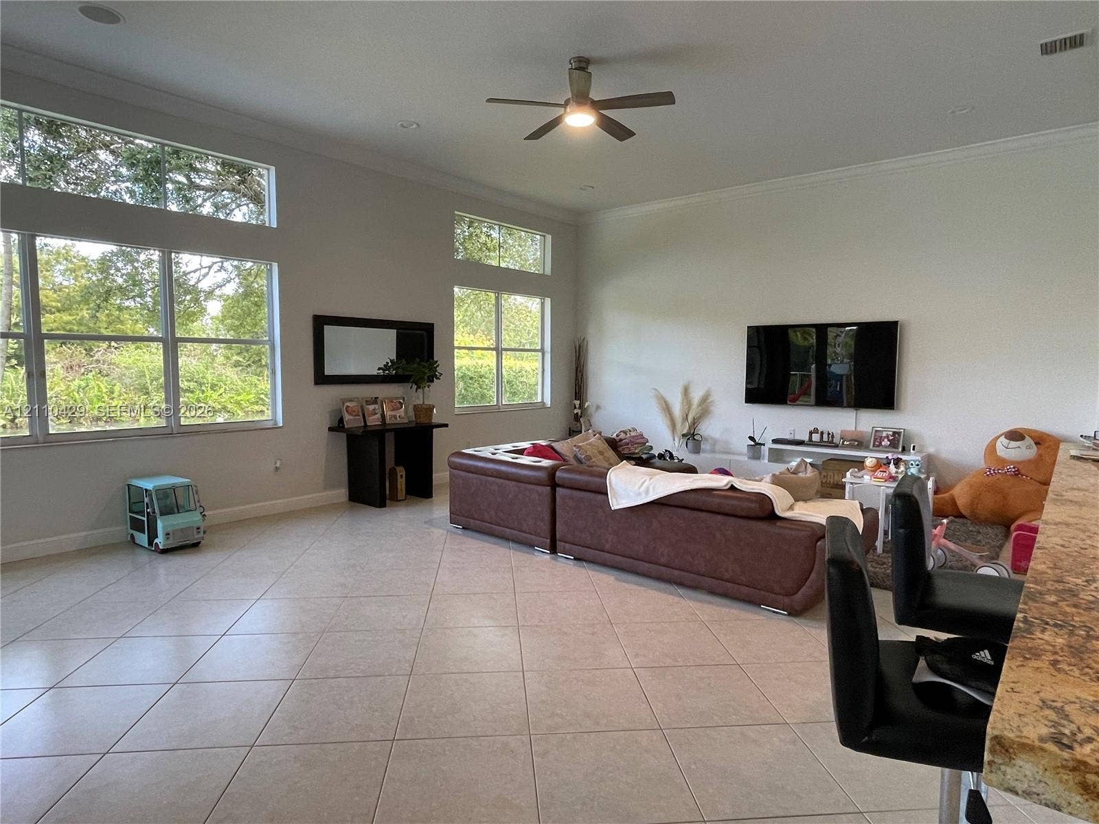 15001 SW 33rd Street, Davie, Davie, FL 33331 Spacious room featuring high ceilings, large windows with clerestory panes, tile flooring, and a ceiling fan
