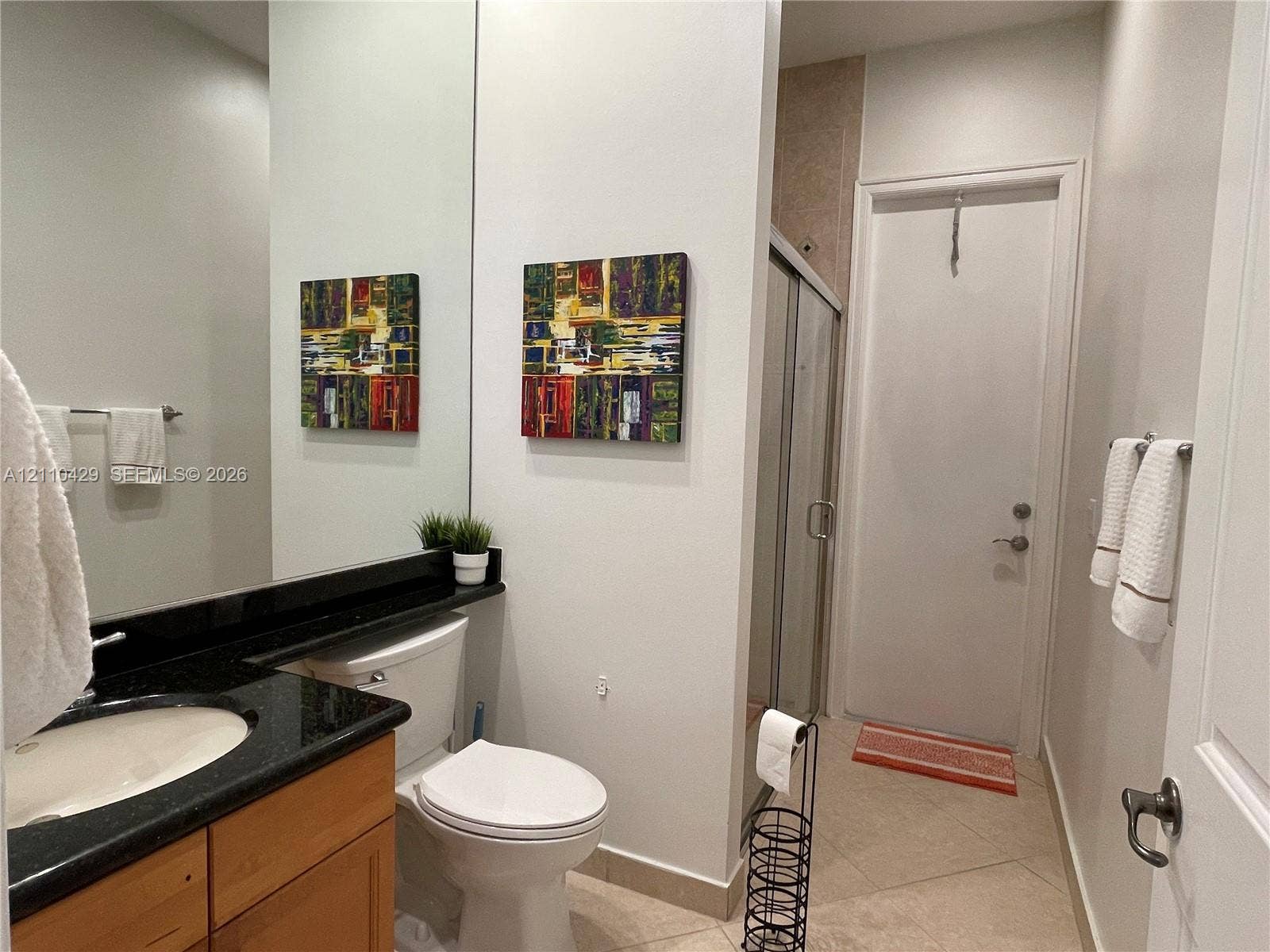 15001 SW 33rd Street, Davie, Davie, FL 33331 Bathroom featuring a vanity with dark stone countertop, integrated sink, wood-finish cabinetry, floor-to-ceiling mirror, and a glass-enclosed shower stall