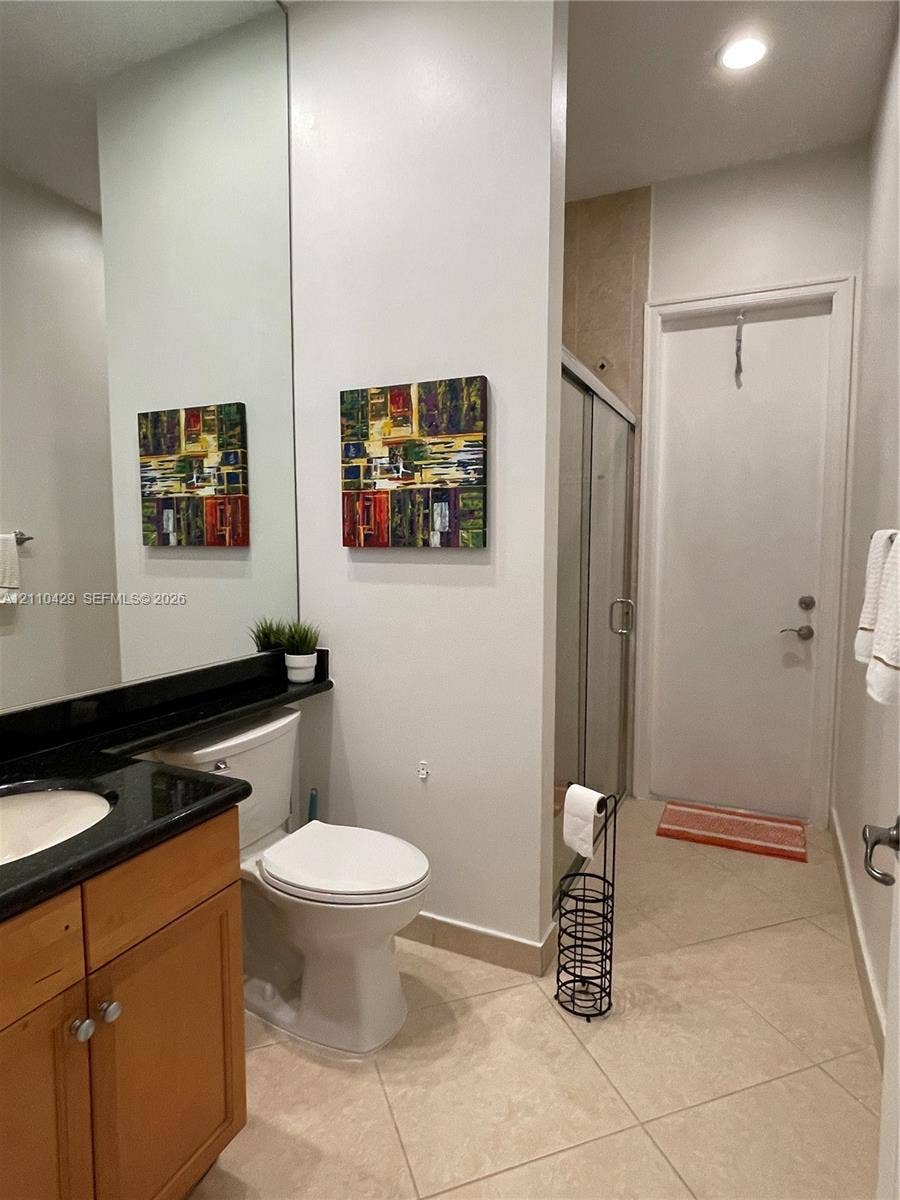 15001 SW 33rd Street, Davie, Davie, FL 33331 Bathroom featuring wood-finish cabinetry, dark countertop with an integrated basin, expansive wall-mounted mirror, and tile flooring