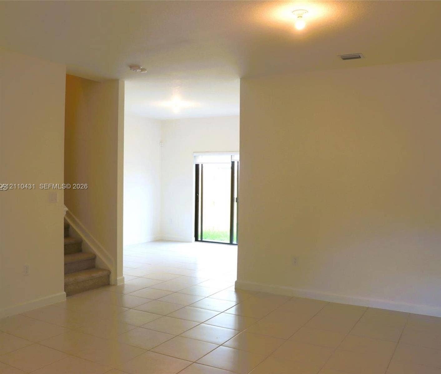 23452 SW 129th Avenue, Homestead, FL 33032 Interior space featuring neutral wall paint, tile flooring, flush-mount ceiling lighting, carpeted staircase, and sliding glass doors