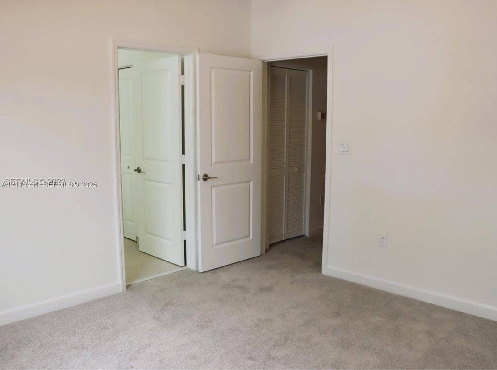 23452 SW 129th Avenue, Homestead, FL 33032 Neutral-toned wall-to-wall carpeting, two-panel interior doors with brushed nickel hardware, and louvered bi-fold closet doors