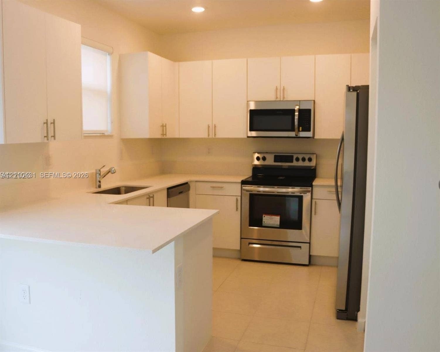 23452 SW 129th Avenue, Homestead, FL 33032 Kitchen featuring white flat-panel cabinetry, light-toned stone countertops, stainless steel appliances, and tile flooring