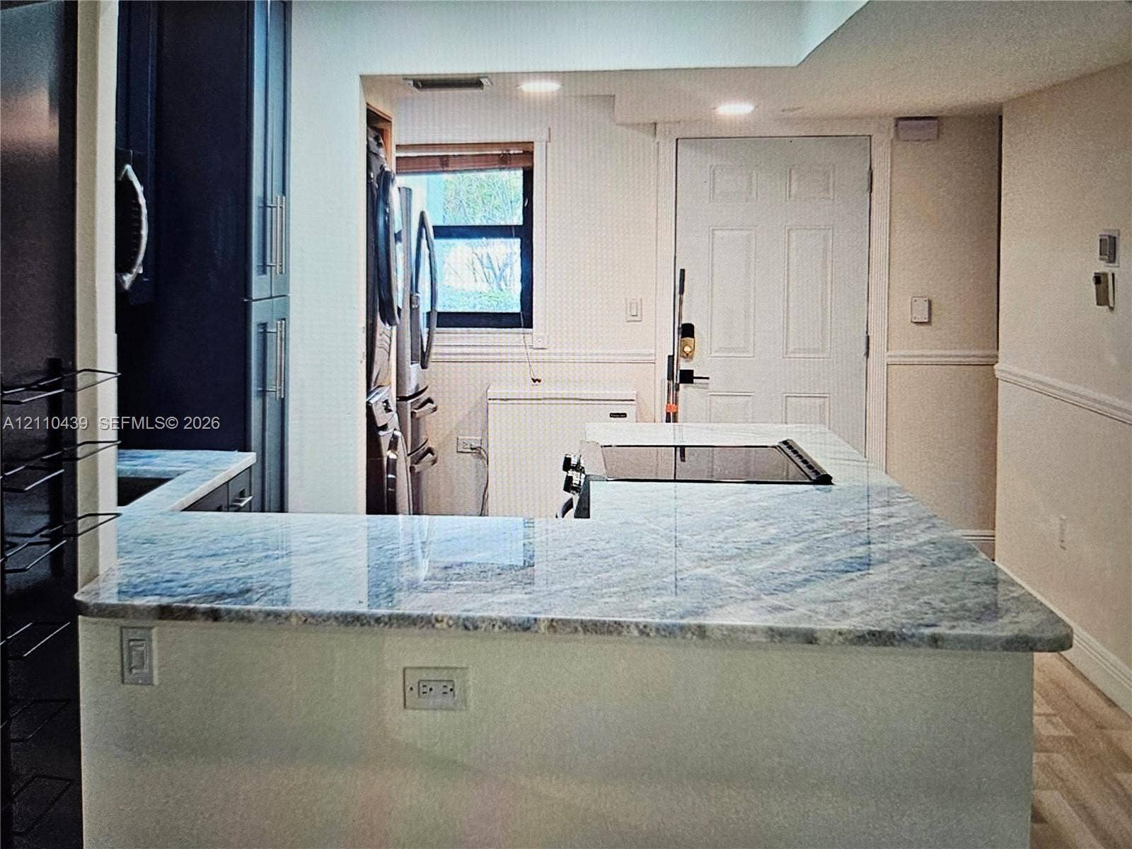 Kitchen featuring a stone-surface peninsula, dark cabinetry, a built-in cooktop, recessed lighting, and wood-finish flooring