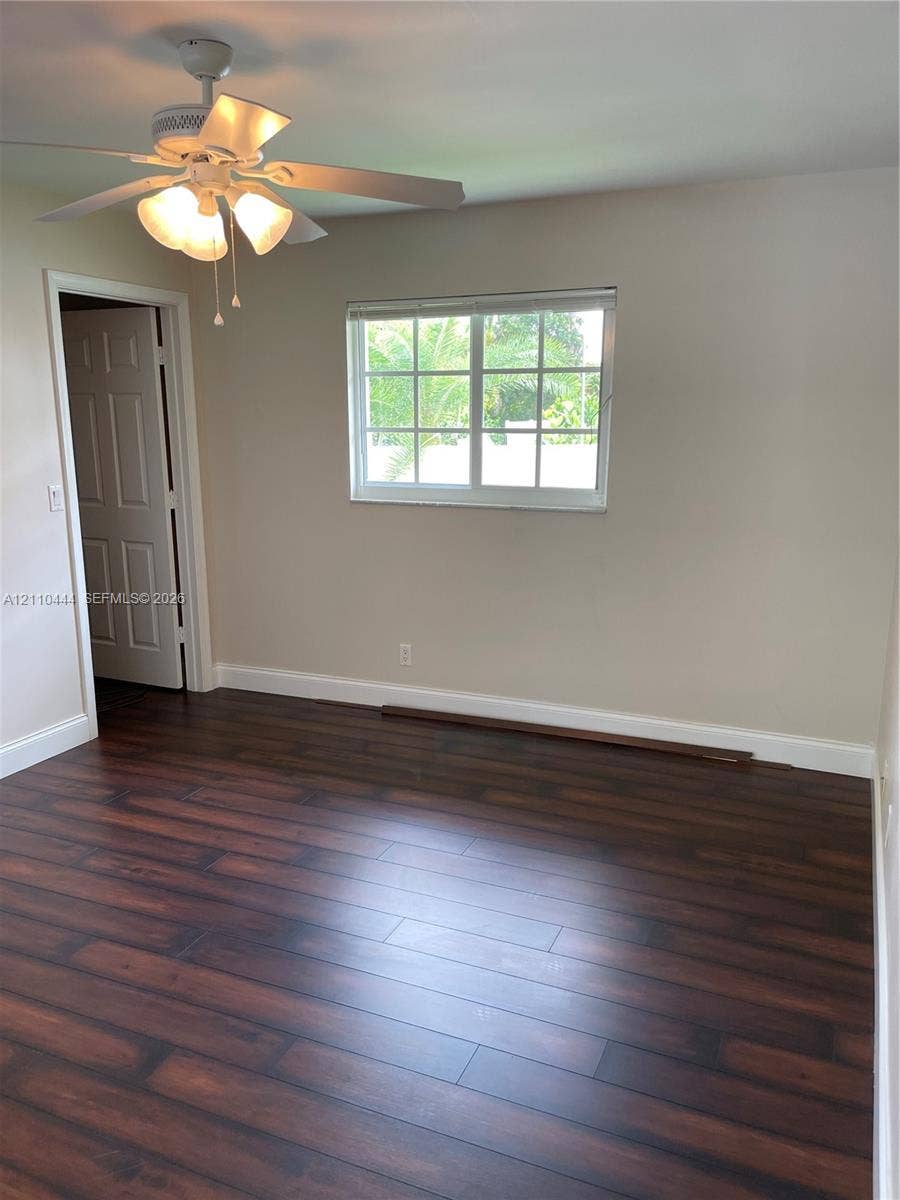 Room featuring wood-finish flooring, a multi-light ceiling fan, a window with muntin detailing, and a six-panel interior door