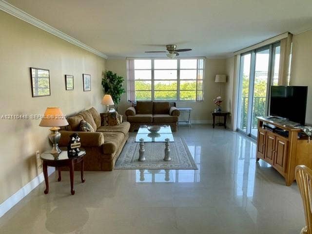 2780 NE 183rd Street, #517, Aventura, FL 33160 Large living area featuring polished tile flooring, crown molding, a central ceiling fan, expansive multi-panel windows, and sliding glass doors