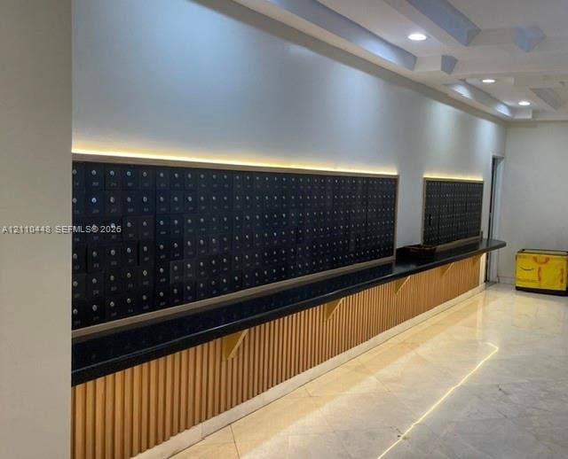 2780 NE 183rd Street, #517, Aventura, FL 33160 Mail center featuring integrated metal mailboxes, stone-surfaced counter, vertical wood-slat detailing, recessed lighting, and tile flooring