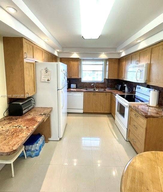 2780 NE 183rd Street, #517, Aventura, FL 33160 Kitchen featuring wood cabinetry, stone countertops, tiled flooring, recessed ceiling lighting, and a double-basin sink