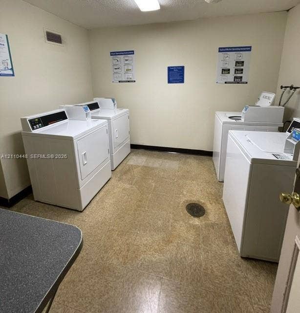 2780 NE 183rd Street, #517, Aventura, FL 33160 Laundry room featuring dual sets of white top-load washers and front-load dryers, resilient tile flooring, and overhead flush-mount lighting