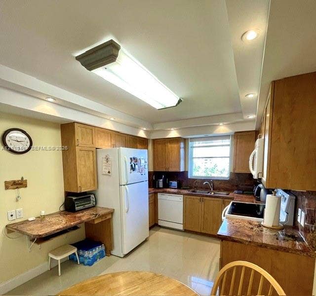 2780 NE 183rd Street, #517, Aventura, FL 33160 Kitchen featuring wood cabinetry, stone-finish countertops, recessed ceiling lighting, a double-basin sink, and tile flooring