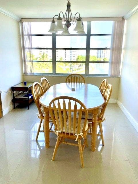 2780 NE 183rd Street, #517, Aventura, FL 33160 Dining area featuring large-format tile flooring, multi-pane floor-to-ceiling windows, and a multi-arm overhead light fixture with glass shades