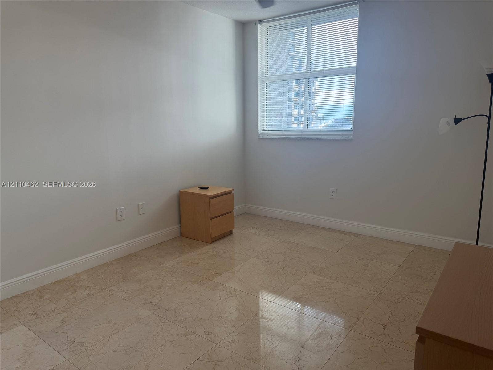 Large room featuring stone tile flooring and a prominent window with horizontal blinds