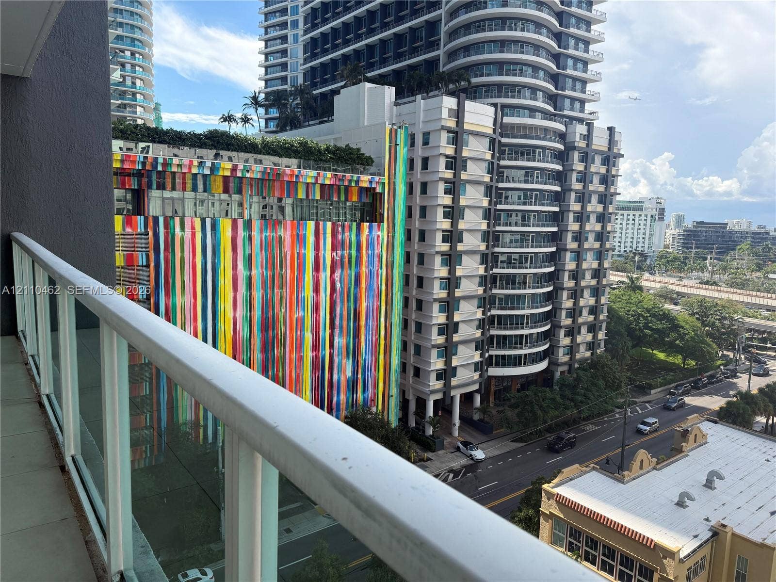Private balcony featuring a white aluminum railing, tile flooring, and urban cityscape exposure
