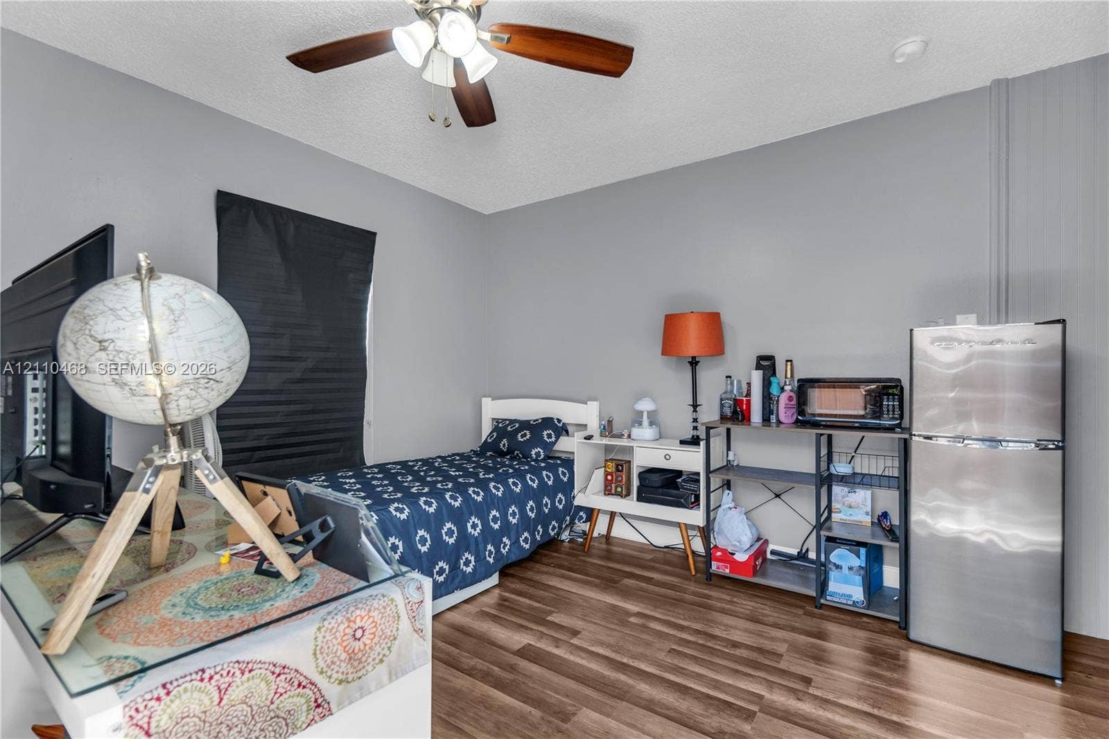 Wood-finish flooring, ceiling fan with integrated lighting, and neutral wall paint