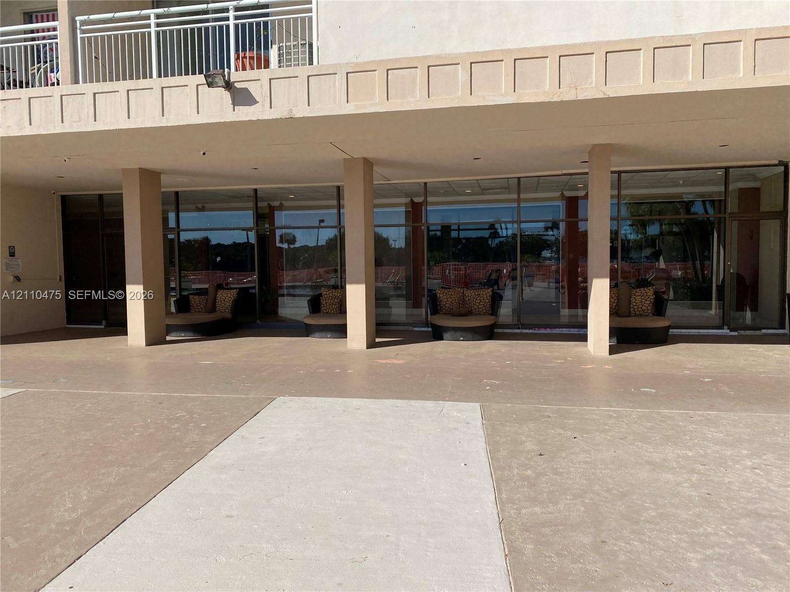 Covered concrete patio featuring floor-to-ceiling glass paneling and structural support columns