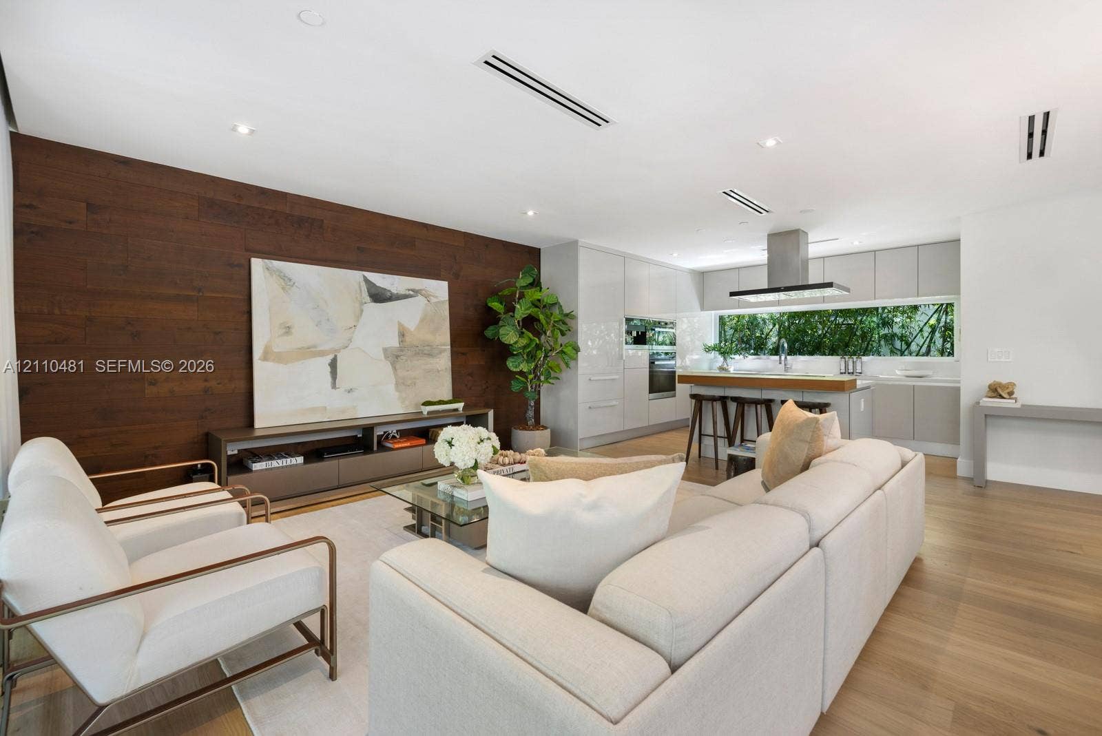 234 Washington Avenue, #D, Miami Beach, FL 33139 Open-concept space featuring wood-finish flooring, a wood-paneled accent wall, flat-panel cabinetry, a stainless steel range hood, and recessed lighting