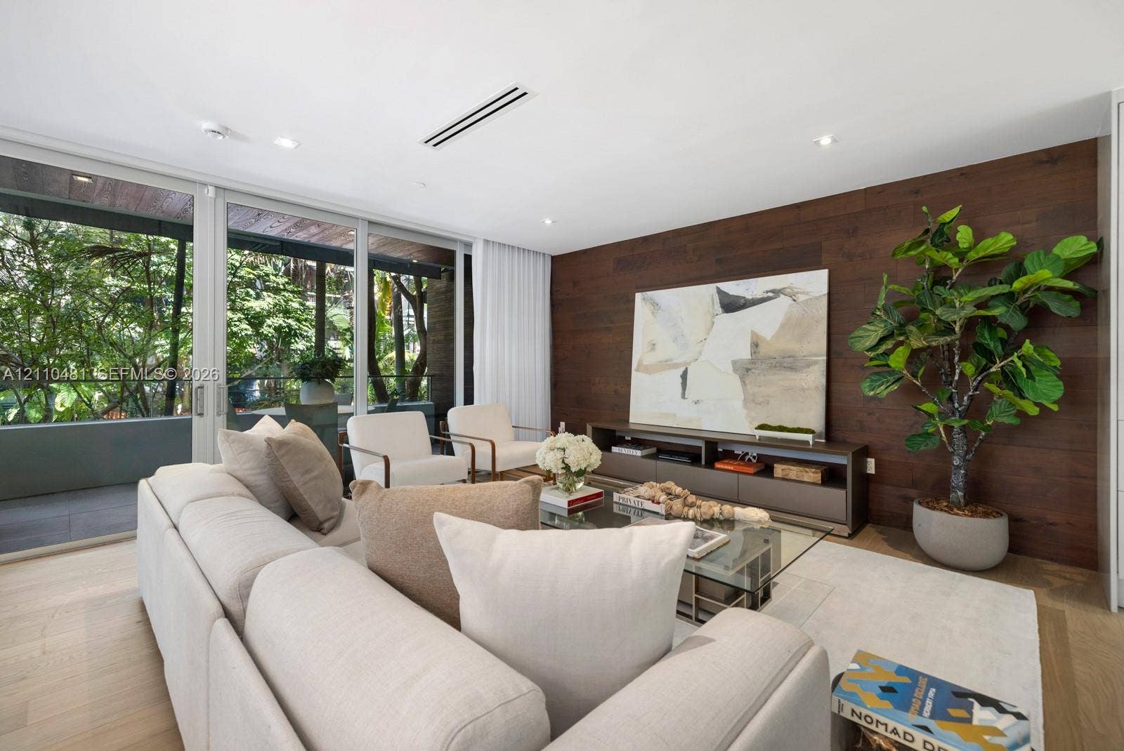234 Washington Avenue, #D, Miami Beach, FL 33139 Living area featuring floor-to-ceiling glass sliding doors, rich wood-plank accent wall, recessed lighting, and light-toned wood-finish flooring
