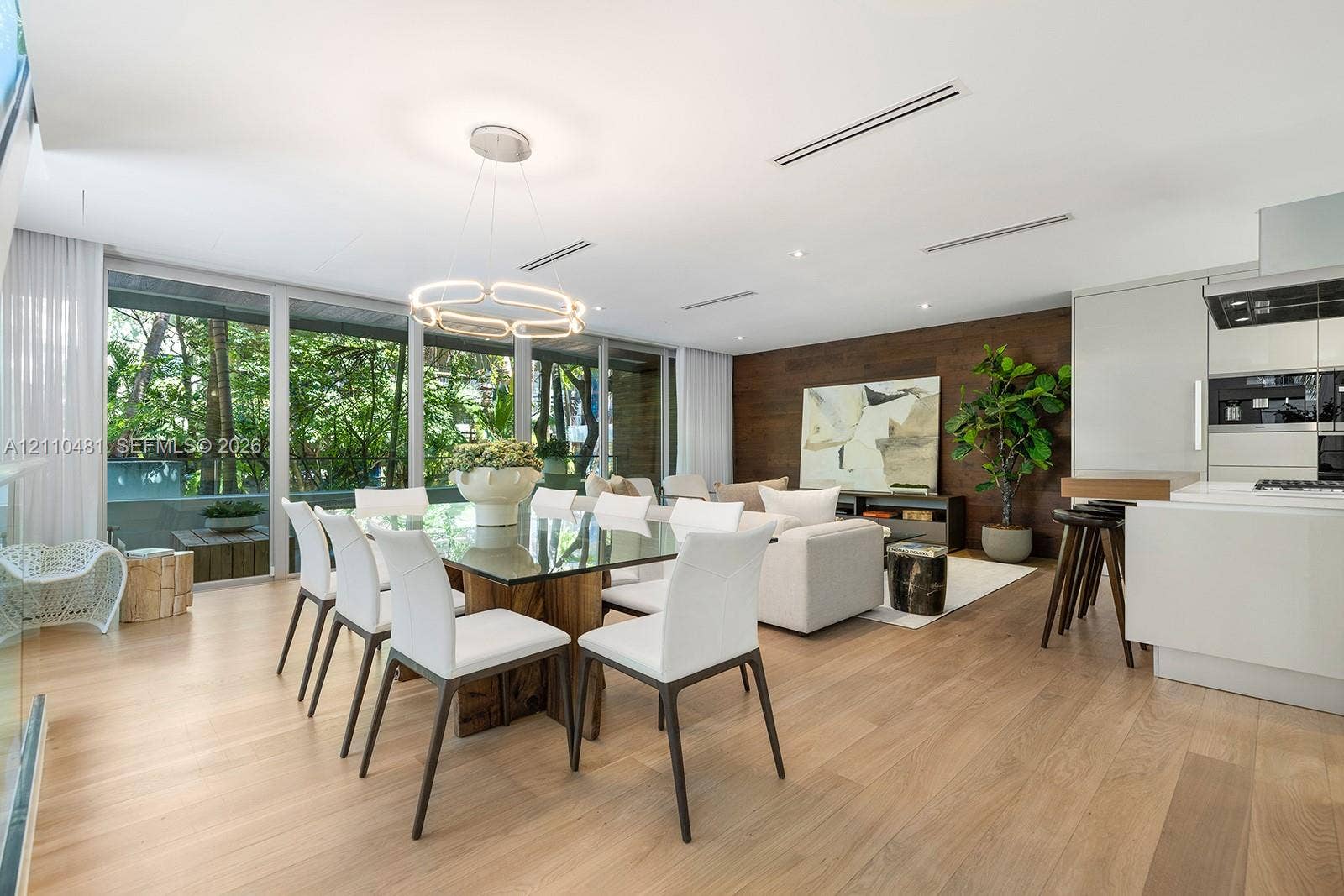 234 Washington Avenue, #D, Miami Beach, FL 33139 Open-concept living space featuring wood-finish flooring, floor-to-ceiling windows, a wood-paneled accent wall, and recessed linear lighting