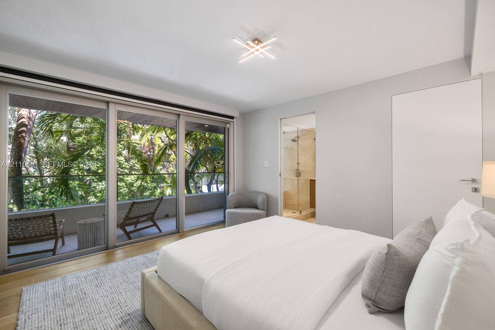 234 Washington Avenue, #D, Miami Beach, FL 33139 Floor-to-ceiling sliding glass doors, wood-finish flooring, recessed modern geometric lighting, and an attached balcony with a glass railing