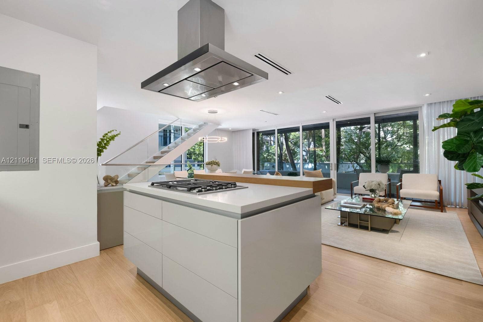 234 Washington Avenue, #D, Miami Beach, FL 33139 Kitchen island featuring a stone countertop, inset gas cooktop, and stainless steel hood range, complemented by wood-finish flooring and floor-to-ceiling windows