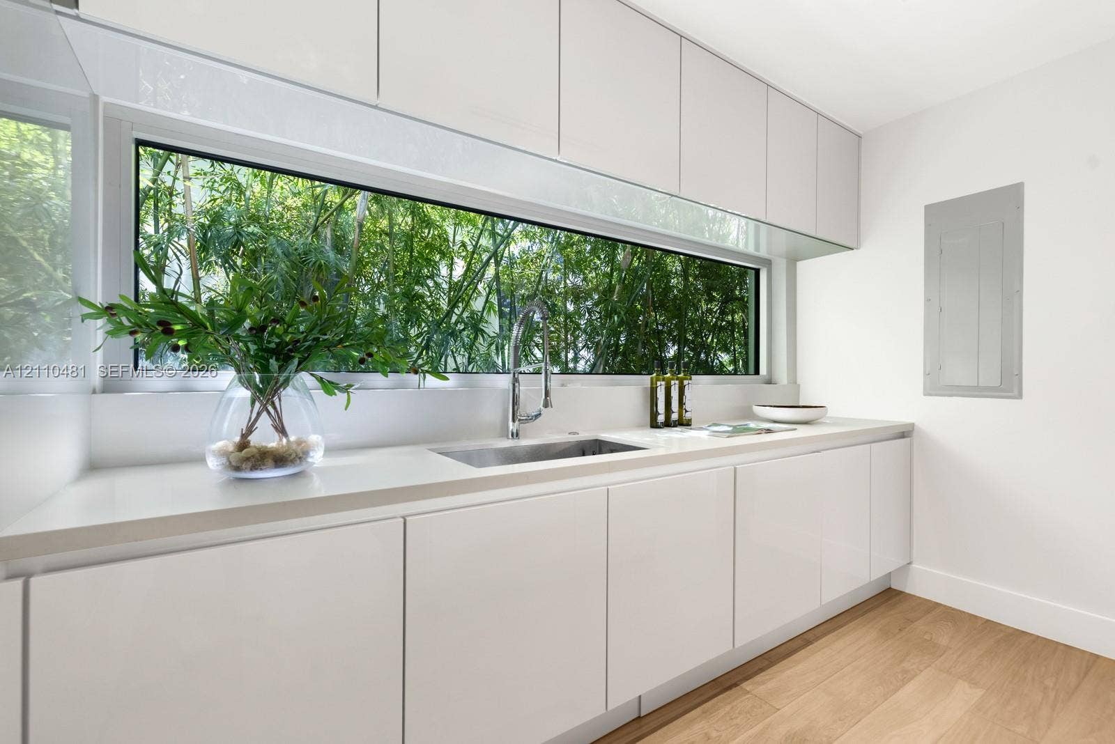 234 Washington Avenue, #D, Miami Beach, FL 33139 High-gloss white cabinetry, expansive horizontal picture window, solid-surface countertop, stainless steel pull-down faucet, and wood-finish flooring