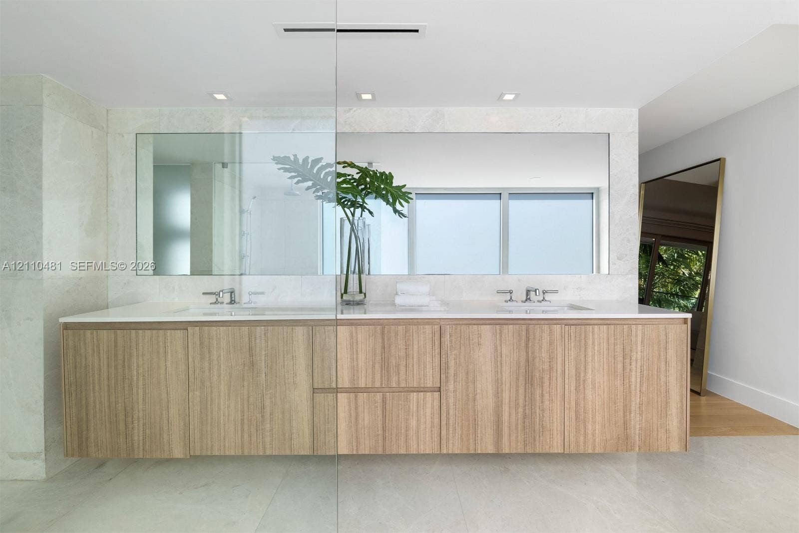234 Washington Avenue, #D, Miami Beach, FL 33139 Floating vanity with wood-finish cabinetry, dual undermount sinks, quartz countertop, polished metal fixtures, and full-width wall mirror