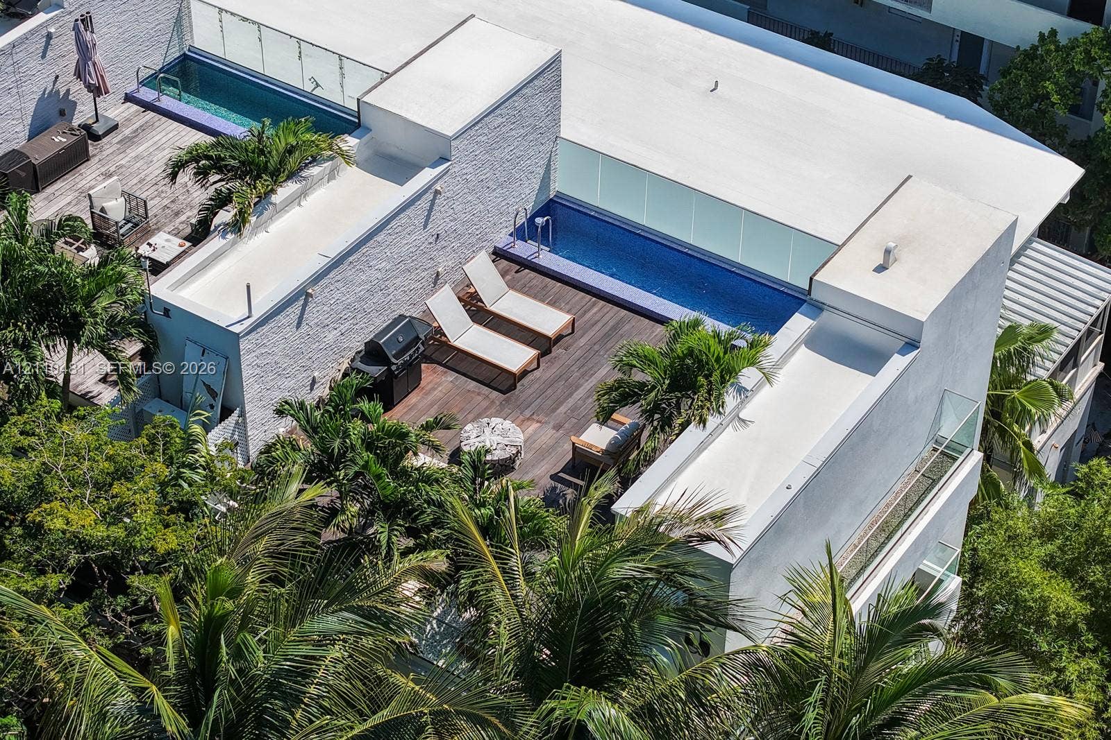 234 Washington Avenue, #D, Miami Beach, FL 33139 Rooftop terrace featuring wood decking, tiled pool, glass railing, and textured exterior wall cladding