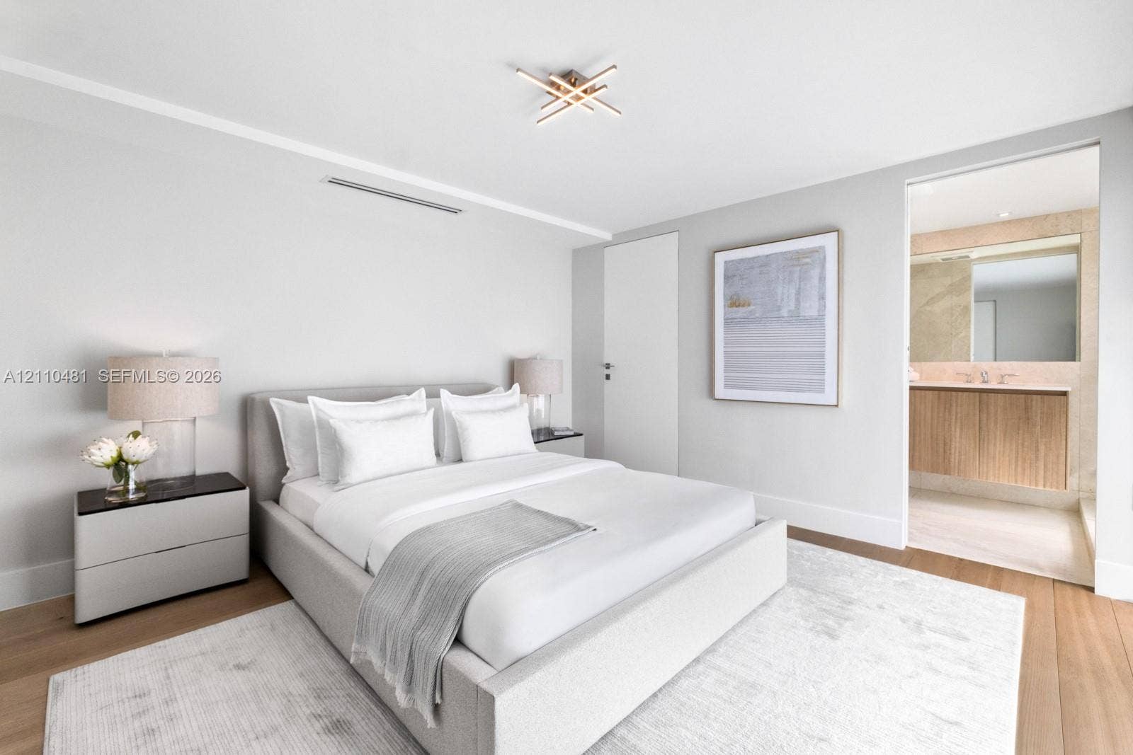 234 Washington Avenue, #D, Miami Beach, FL 33139 Modern bedroom featuring wide-plank wood-finish flooring, a linear ceiling light fixture, and an ensuite bathroom with a floating vanity and natural stone wall accents