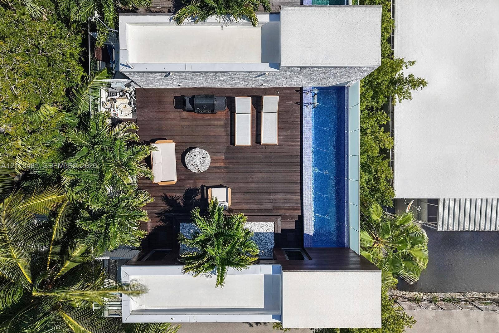 234 Washington Avenue, #D, Miami Beach, FL 33139 Expansive wood-finish decking featuring a built-in swimming pool, integrated hardscaping, and surrounding mature tropical vegetation