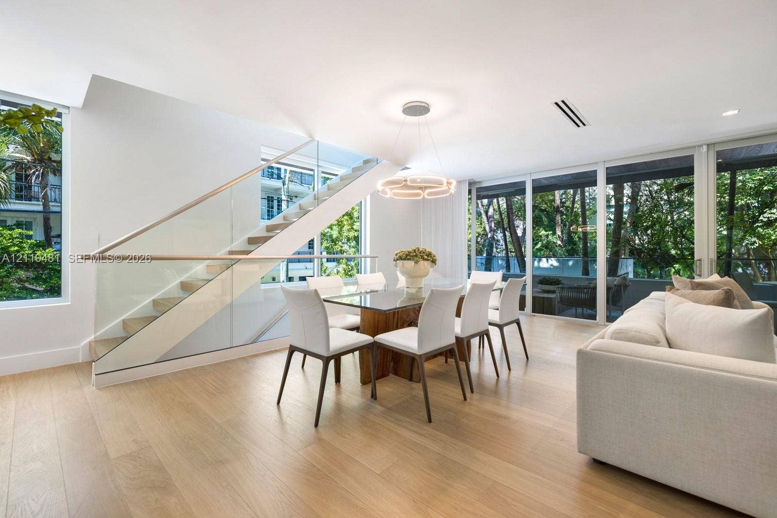 234 Washington Avenue, #D, Miami Beach, FL 33139 Open-plan interior featuring light wood-finish flooring, floor-to-ceiling glass panels, and a staircase with glass railings and a wood handrail