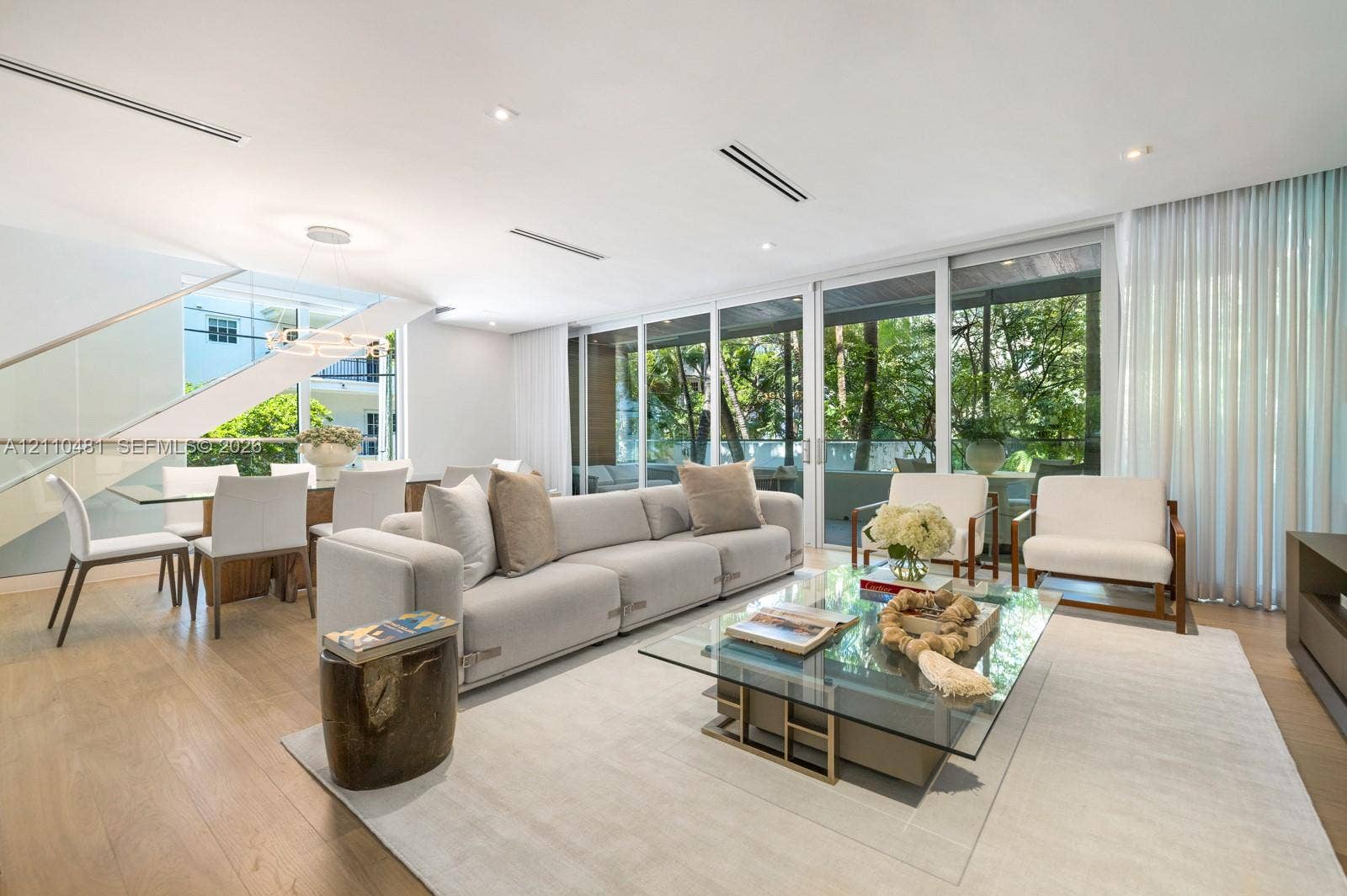 234 Washington Avenue, #D, Miami Beach, FL 33139 Open-concept living space featuring wood-finish flooring, floor-to-ceiling glass sliding doors, recessed ceiling lighting, and a floating staircase with a glass railing