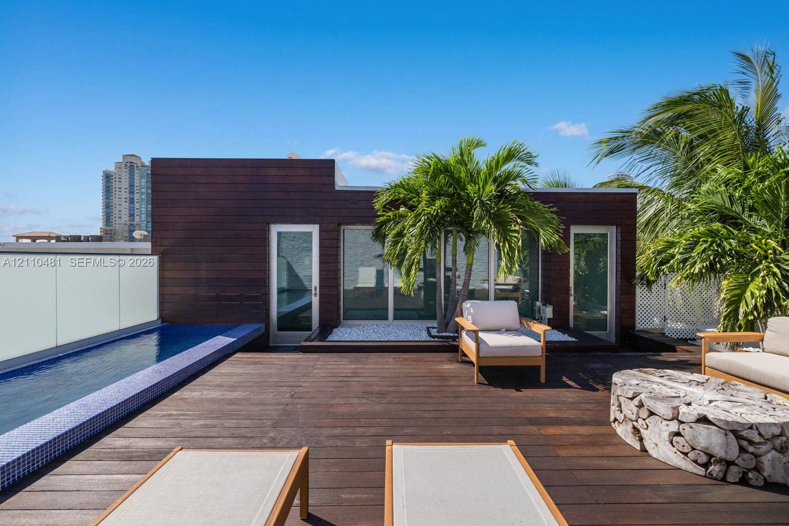 234 Washington Avenue, #D, Miami Beach, FL 33139 Rooftop terrace featuring dark wood decking, a built-in lap pool with mosaic tile surround, opaque glass railing, and wood-paneled exterior siding