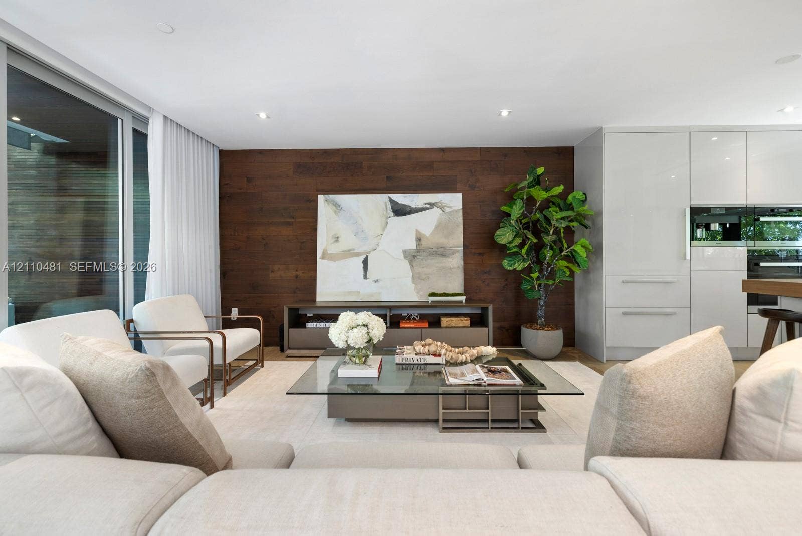 234 Washington Avenue, #D, Miami Beach, FL 33139 Open-concept interior featuring wood-paneled accent wall, recessed lighting, expansive floor-to-ceiling windows, and white cabinetry with integrated appliances