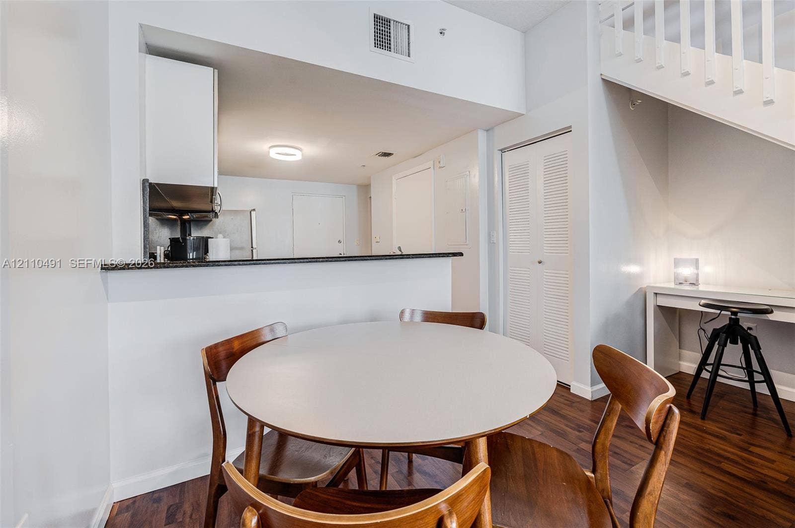 3339 Virginia Street, #136, Miami, Miami, FL 33133 Kitchen featuring a dark stone countertop, wood-finish flooring, and a built-in staircase with white wooden railings