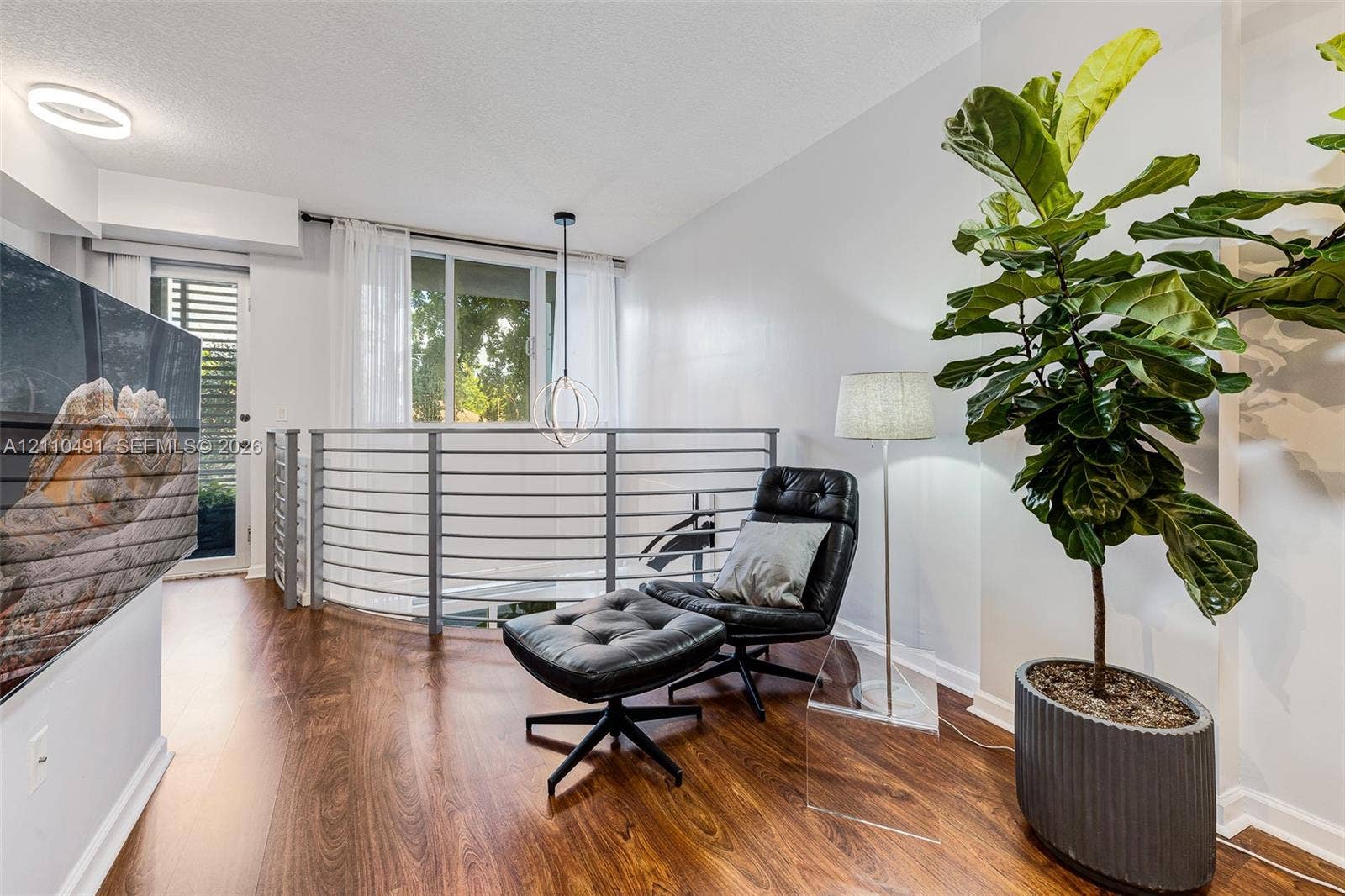 3339 Virginia Street, #136, Miami, Miami, FL 33133 Open-concept loft area featuring wood-finish flooring, a contemporary circular pendant light, integrated horizontal metal railing, and recessed ceiling lighting