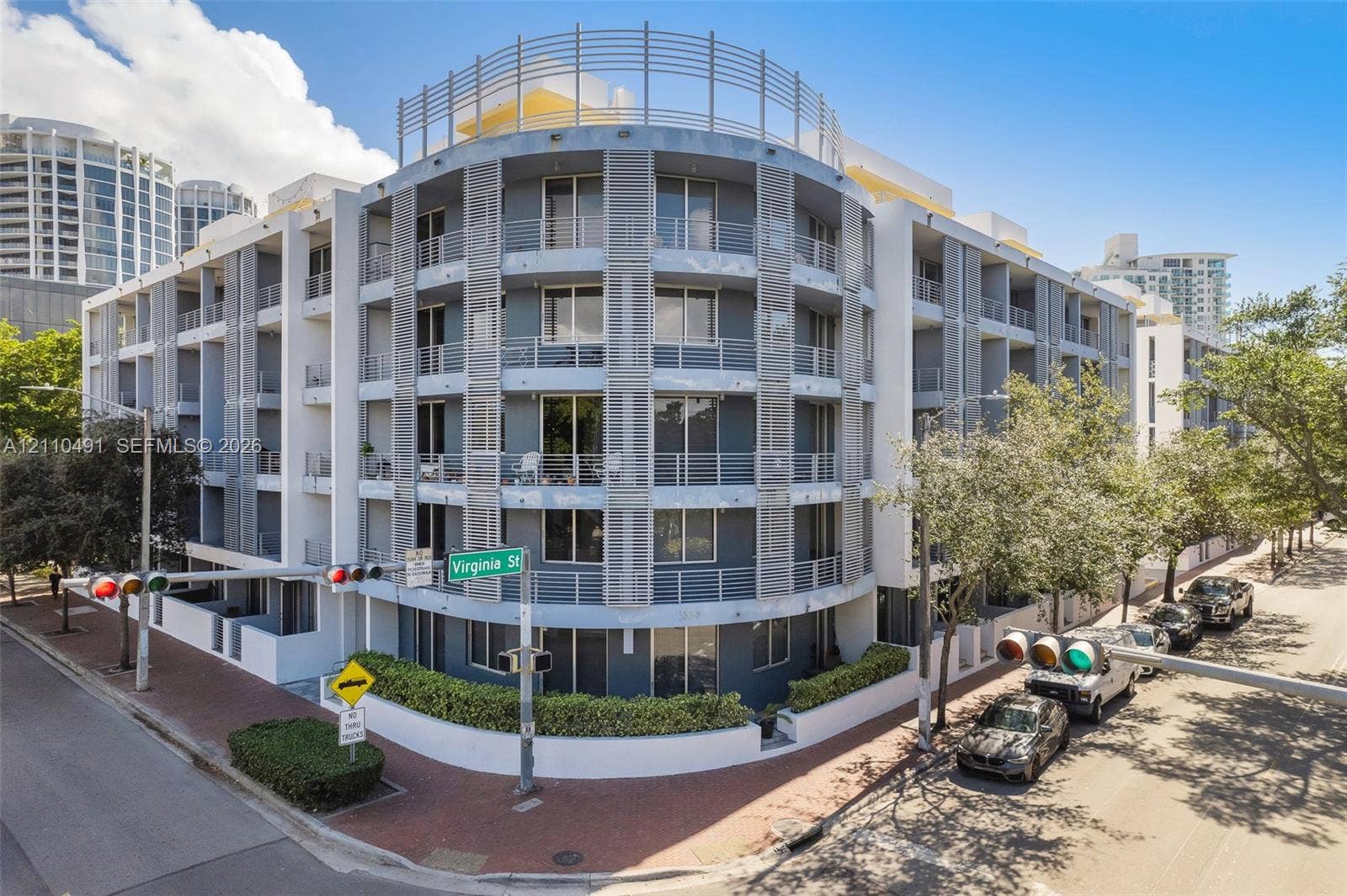 3339 Virginia Street, #136, Miami, Miami, FL 33133 Multi-story contemporary exterior featuring curved architectural design, private recessed balconies, metallic louvered screening, and ground-level perimeter landscaping