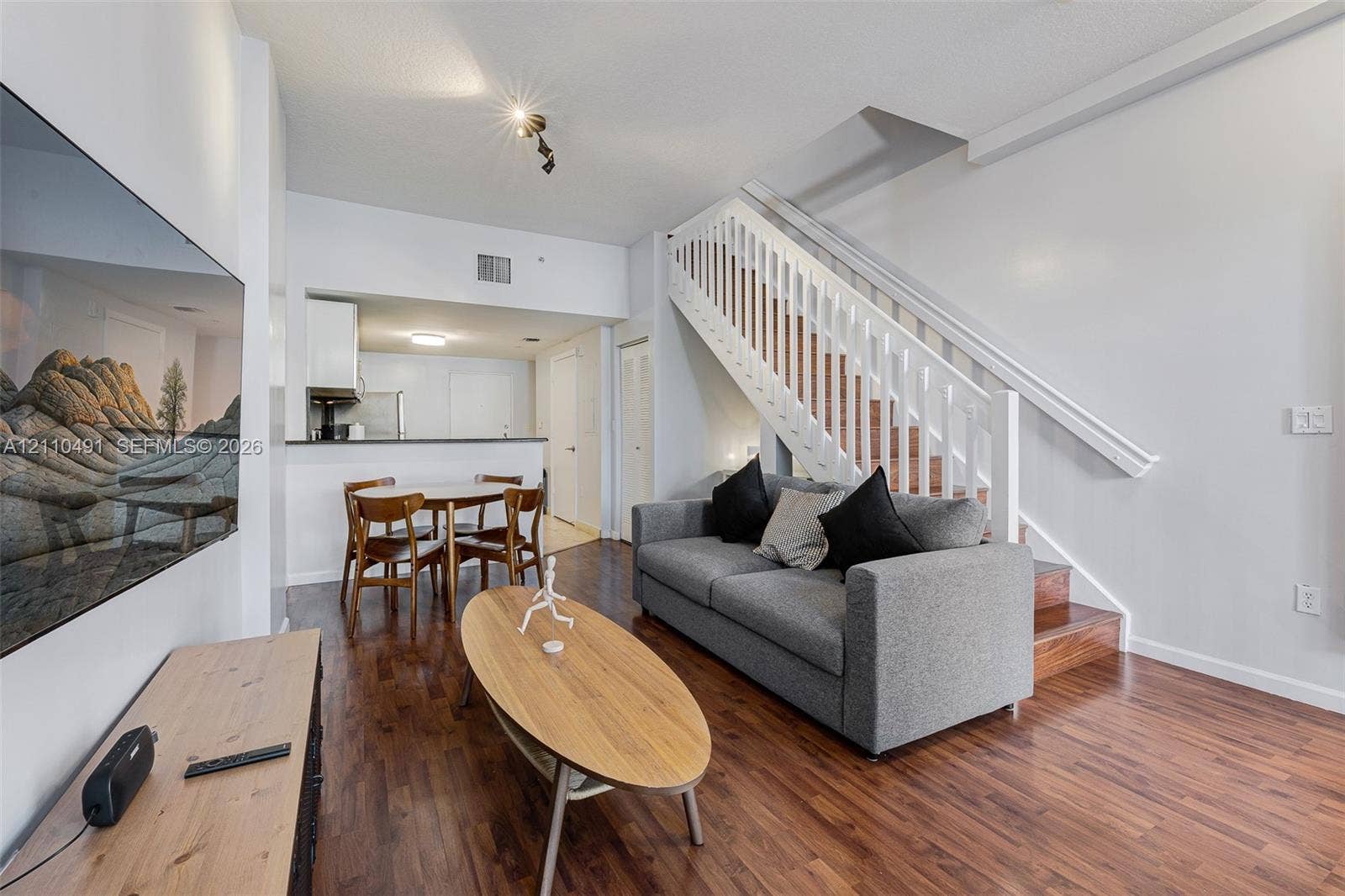3339 Virginia Street, #136, Miami, Miami, FL 33133 Wood-finish flooring throughout, white staircase with handrail, and kitchen featuring a breakfast bar