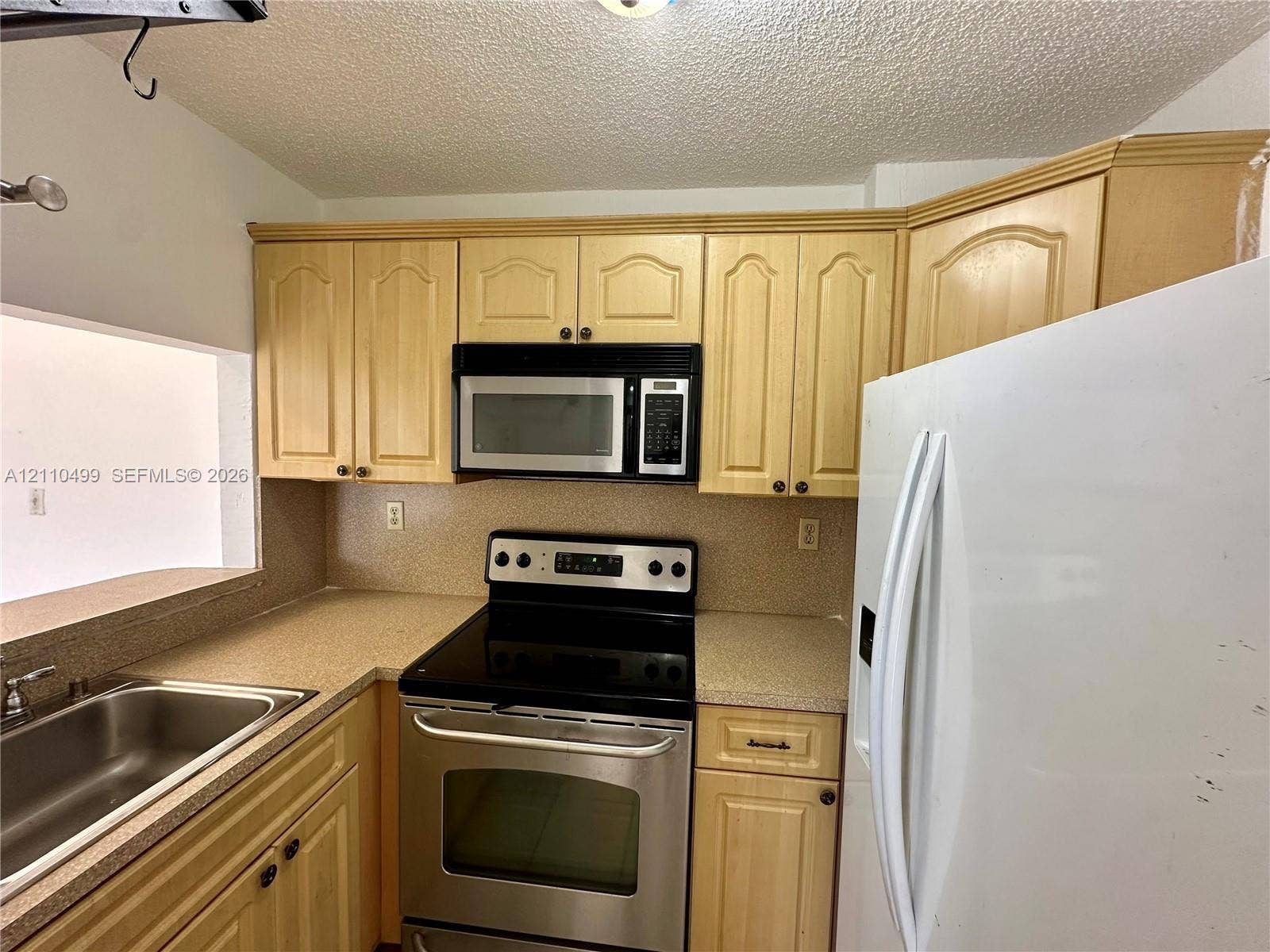 8145 NW 7th Street, #308, Miami, Miami, FL 33126 Kitchen featuring light-finish cabinetry, solid-surface countertops, stainless steel electric range, over-the-range microwave, and undermount stainless steel sink